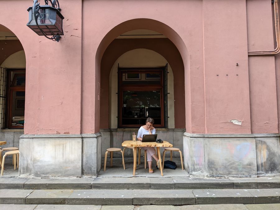 a woman using a laptop while sitting on a chair — Plazas and promenades: video calls home with the view behind you.