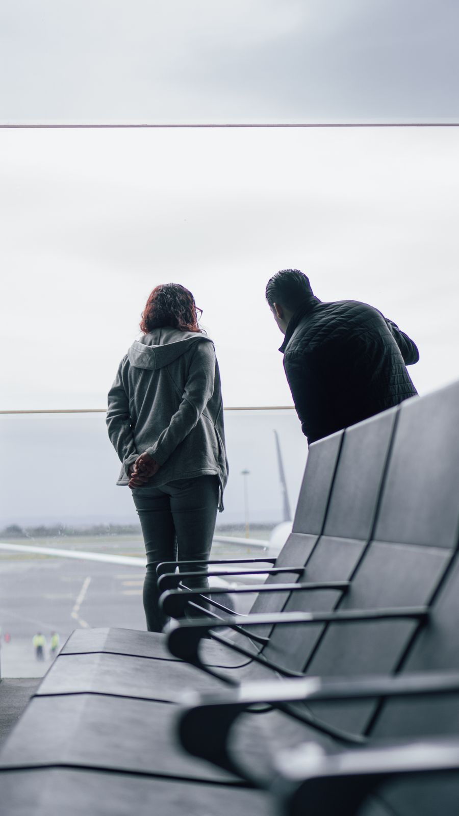 woman and man standing near windows on airport — 晴れでも雨でも接続は維持 — 天気でデータが絞られることはありません。