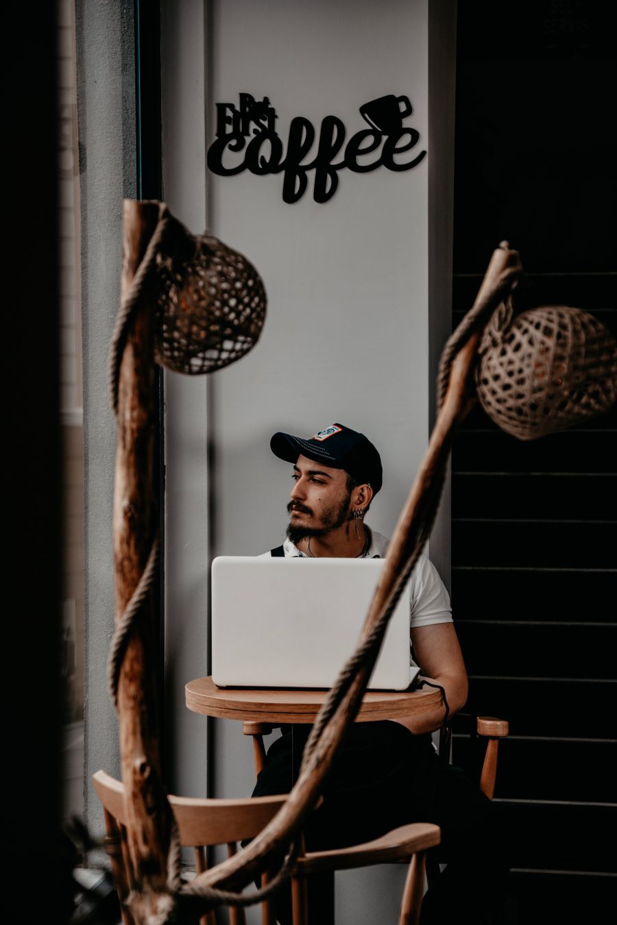 man in cap sitting by table with laptop — Old town, new tricks: translation apps working in real time.