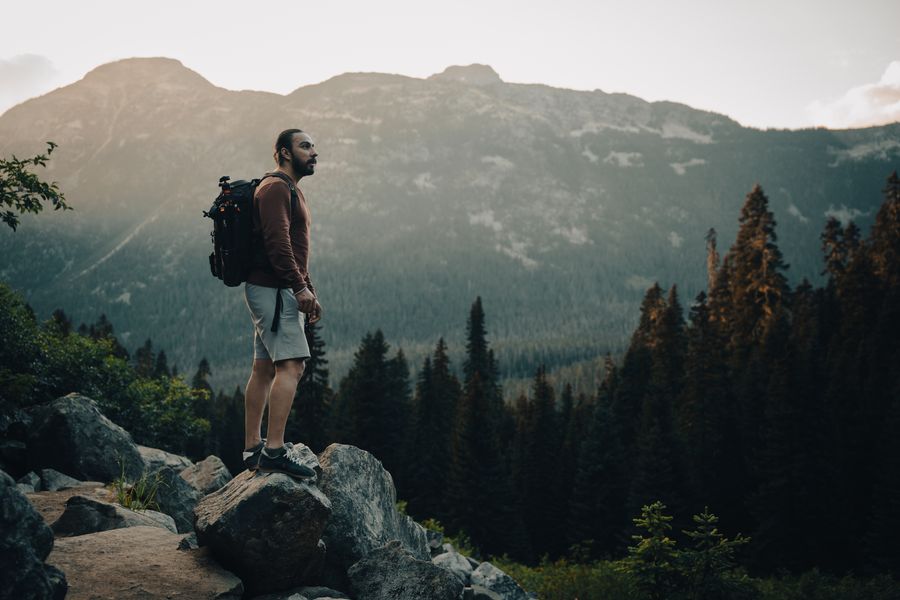 man with a backpack standing on a rock — From departure lounge to arrival hall, the data never drops.