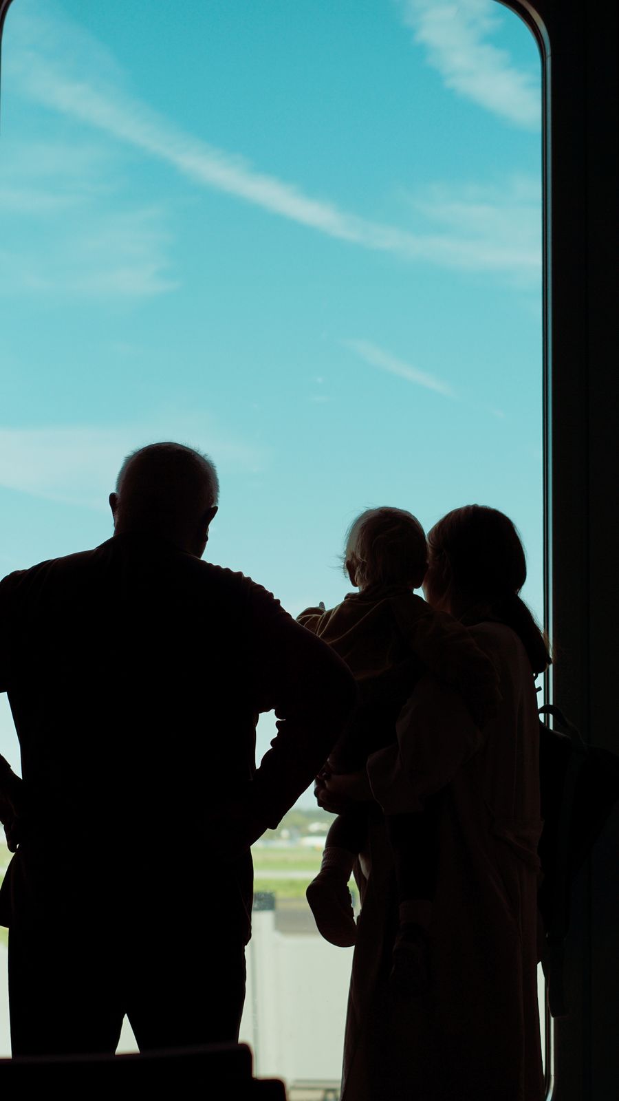 silhouette of a family looking out of a window at an airplane