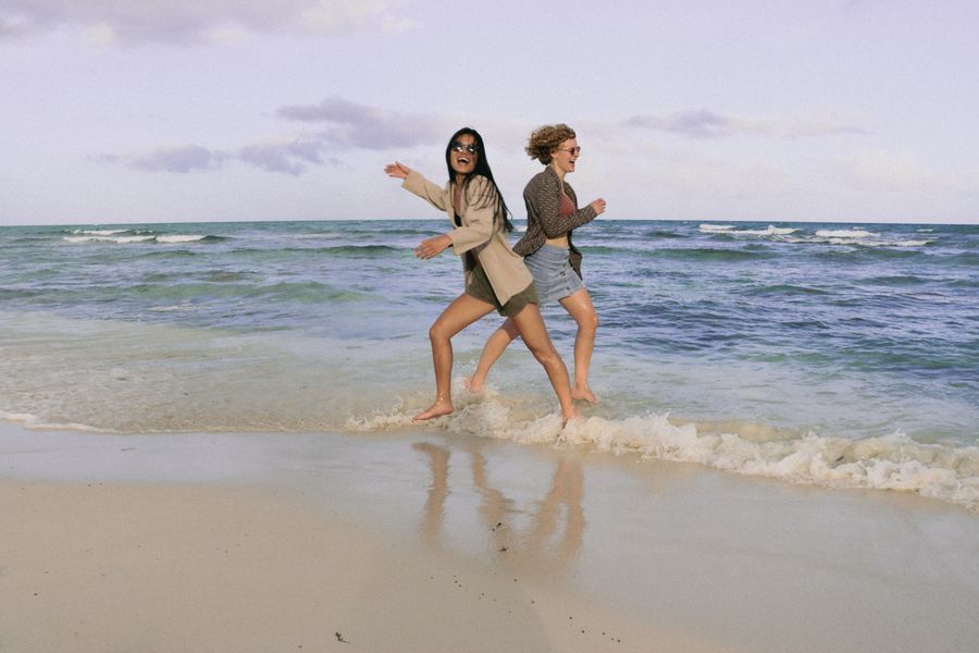 smiling women running on sea shore