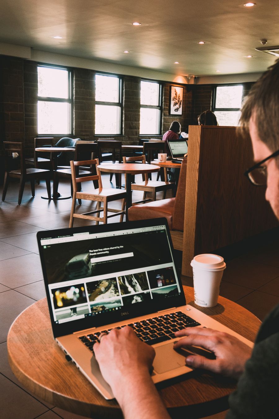 man using macbook on wooden table — 出発案内板が切り替わる：ゲート発見、ラウンジ特定、すべてeSIMで。