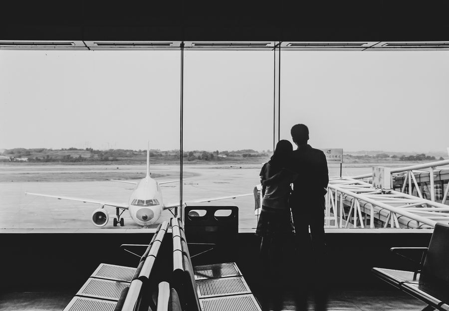 back view of couple embracing at airport — Souvenir hunting with live currency conversion in your pocket.