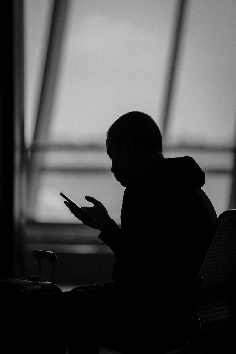 Silhouette of a man using a smartphone in an airport terminal in Surabaya, Indonesia. — Docs: 日の出ハイキングは天気確認から — データオン、ブーツオン。