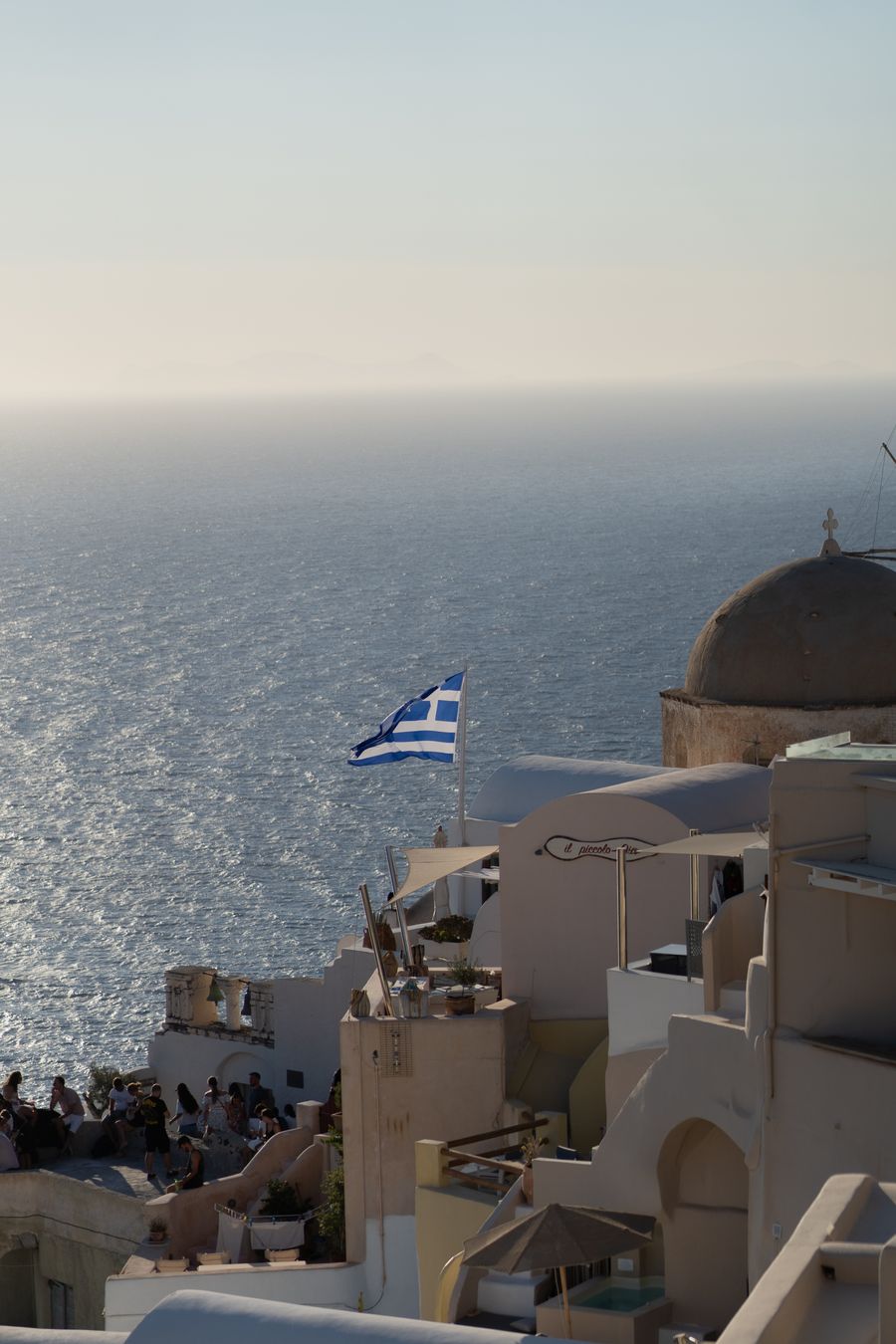 a view of a beach with a greek flag flying — Docs: 都心部も接続：eSIMが最速の現地ネットワークを自動で検出。