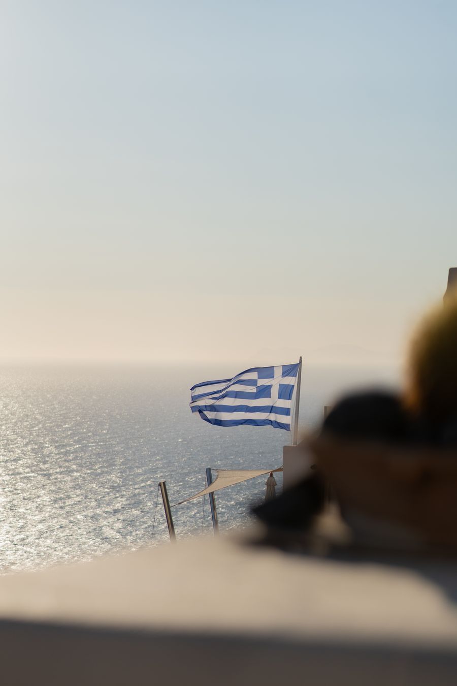 a greek flag is flying over the ocean — 夜行バス:エンタメはダウンロード済み、メッセージはキューに、安心してお休みを。