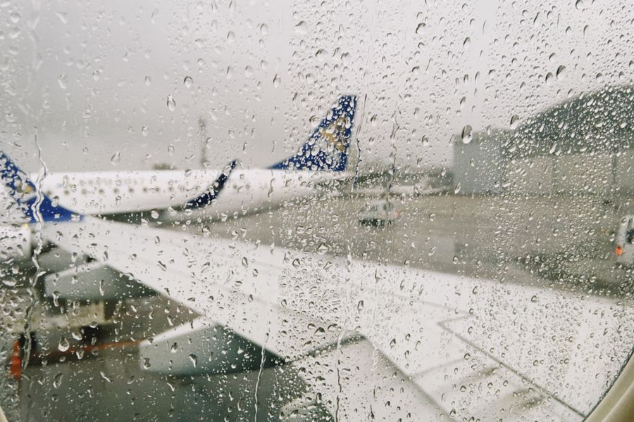 rainy airport view from airplane window — Night markets and late trains — connected the whole way through.