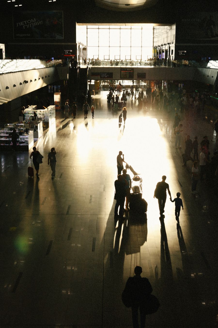 busy airport terminal with silhouetted travelers — 航空会社の確認SMSは旅の番号に即座に届きます。