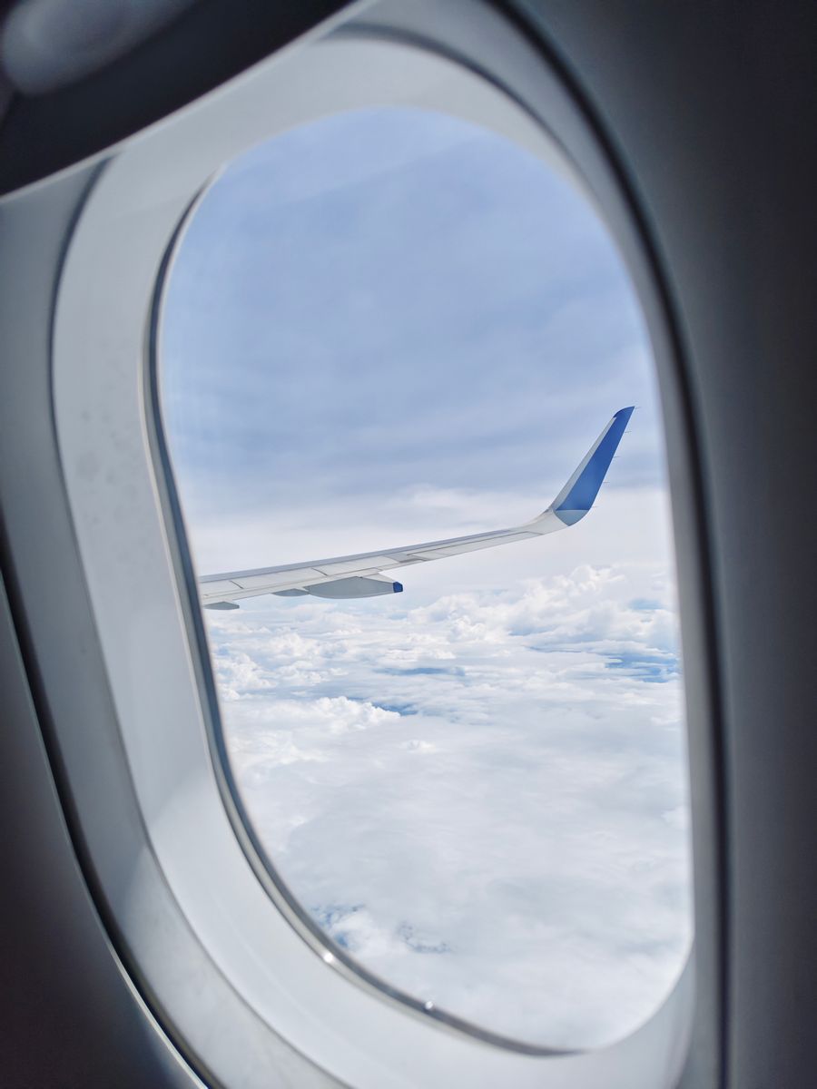 view of airplane wing and clouds from cabin — Souvenir hunting with live currency conversion in your pocket.