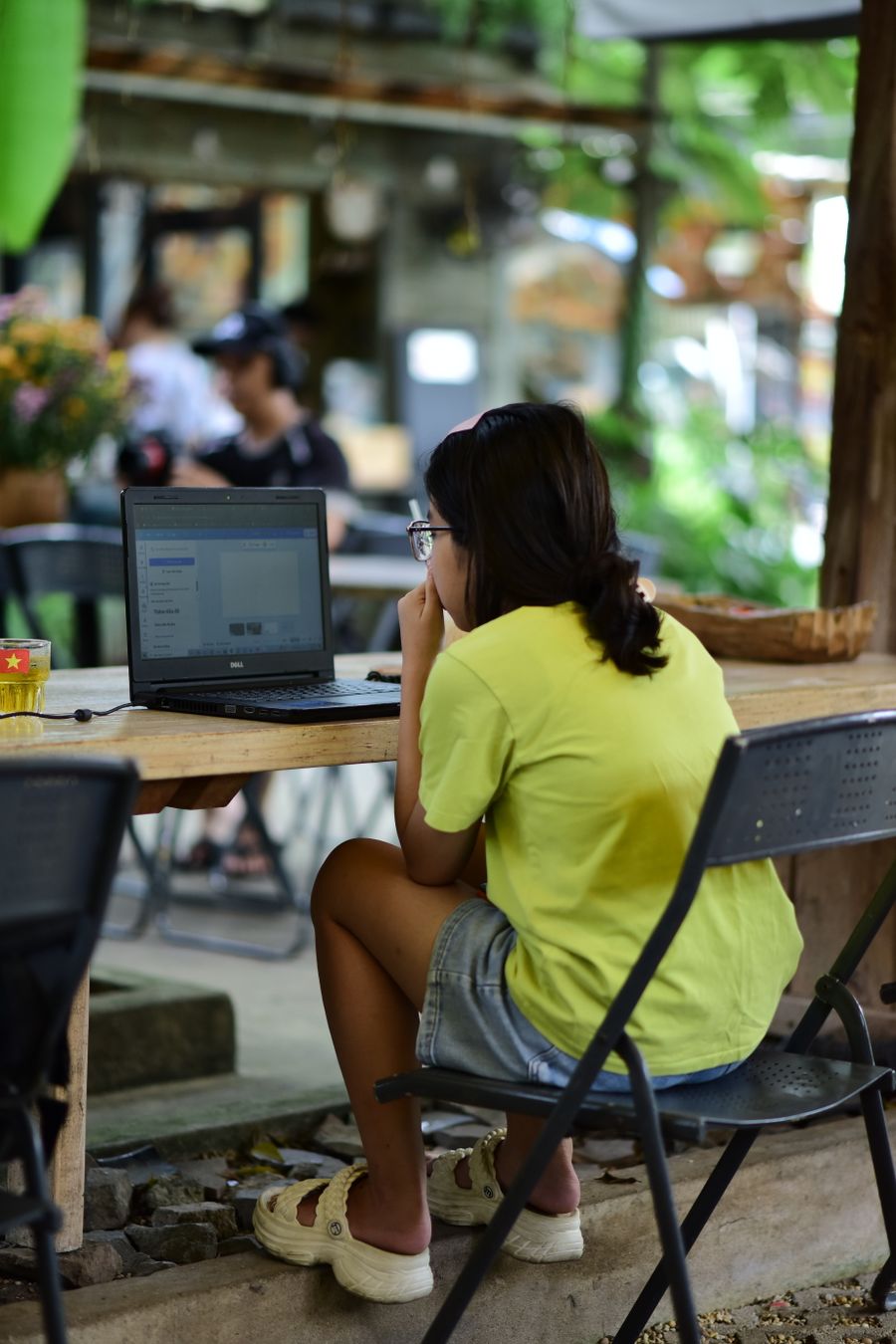 woman working on laptop in outdoor cafe setting — Support: 海岸道路も田舎道も — どこへ行っても地図がついてきます。