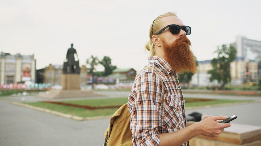 Hipster with a beard and sunglasses in a city square holding a smartphone. — Dual-SIM Setup Guide remembers, so repeat travelers barely type.