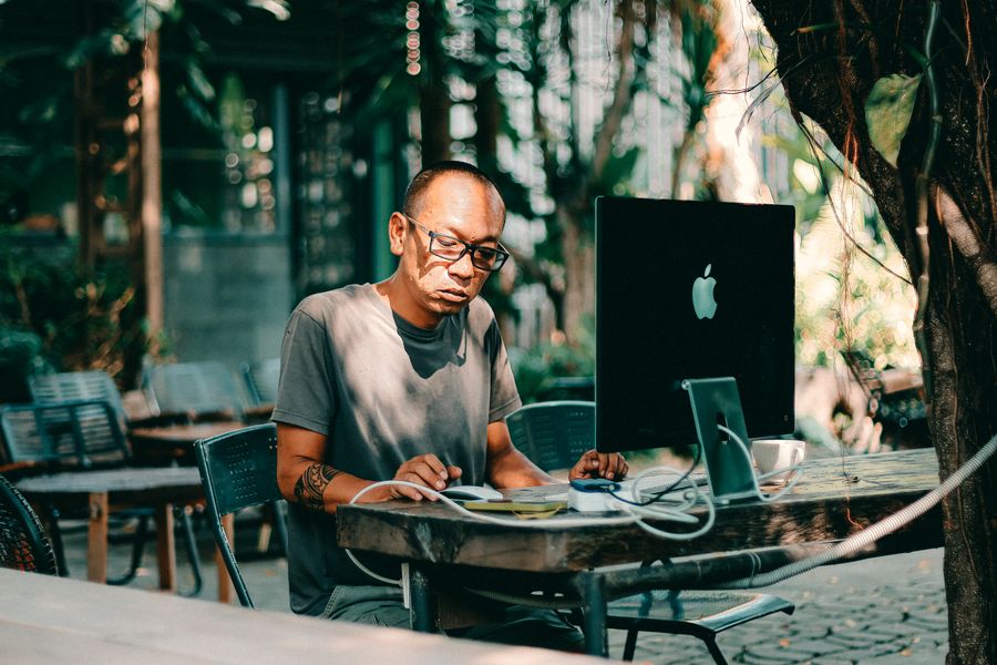 man working on computer at outdoor cafe — Travelers stay online from the moment they land — no SIM queues, no roaming shock.