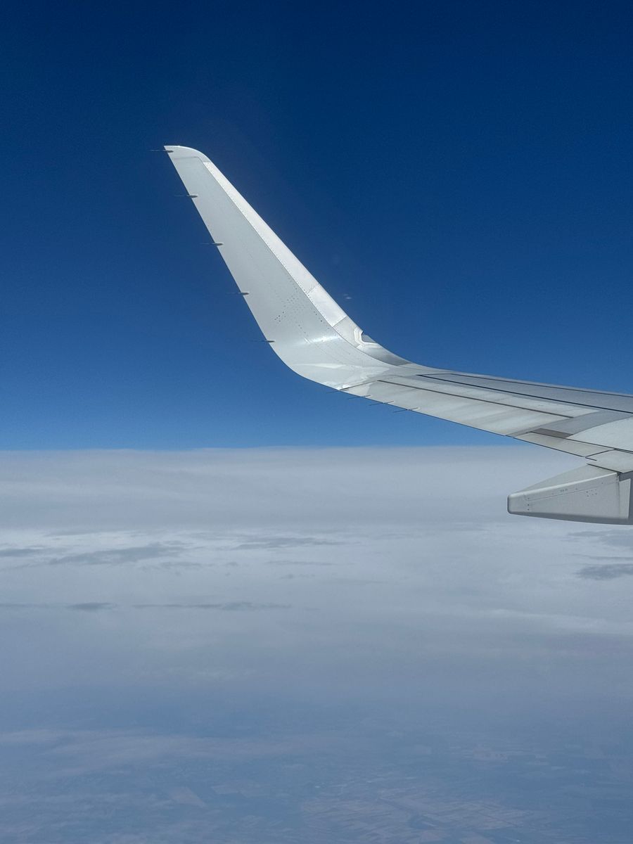 airplane wing above the clouds on a clear day — Support: 通勤は万全：ポッドキャストはダウンロード済み、メッセージ送信済み、圏外なし。