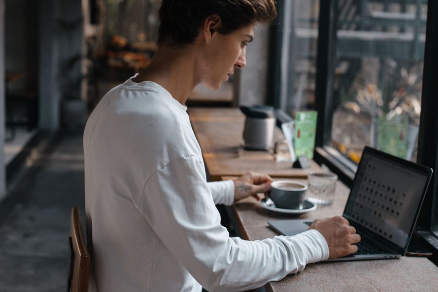 man working on laptop inside cafe — スマホはeSIMを他の回線と同様に扱います — モバイルデータ用に選択してください。