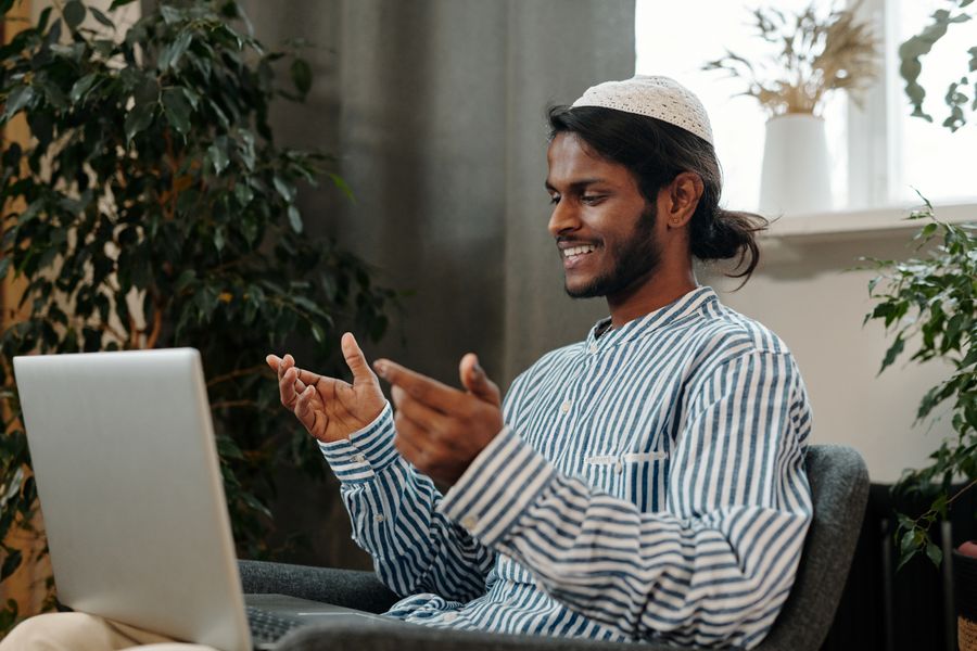 man video calling using a laptop while sitting on a chair