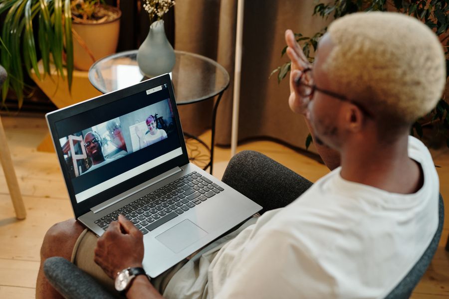man video calling using a laptop while sitting on a chair — Developers: 出発案内板が切り替わる:ゲート発見、ラウンジ特定、すべてeSIMで。