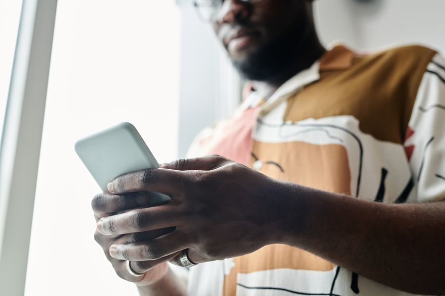 close up shot of a man using a smartphone — Developers: 深夜便からの回復:フライト中にホテルのアーリーチェックインを手配。