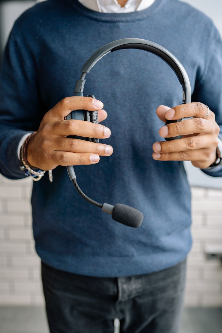 close up shot of a person in blue sweater holding a black headset — Six use cases, one tool — planners, sprinters, remote workers, families.