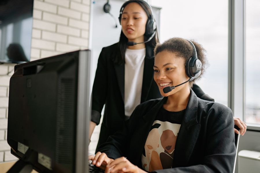 two women with headsets working as call center agents — Duty-free browsing: price-checked against home before buying.